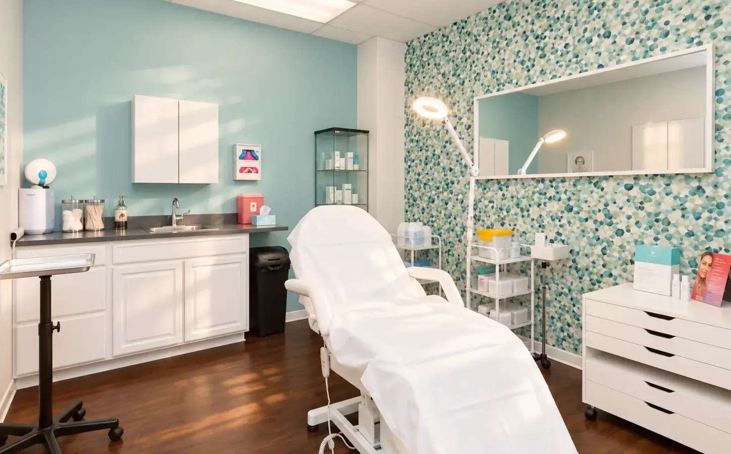A treatment room at Skinovatio Arlington Heights, with a reclining chair, a magnifying lamp and a teal mosaic tile wall